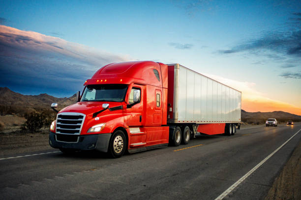 istockphoto-1465157700-612x612 Brightly Red Colored Semi-Truck Speeding on a Two-Lane Highway with Cars in Background Under a Stunning Sunset in the American Southwest
